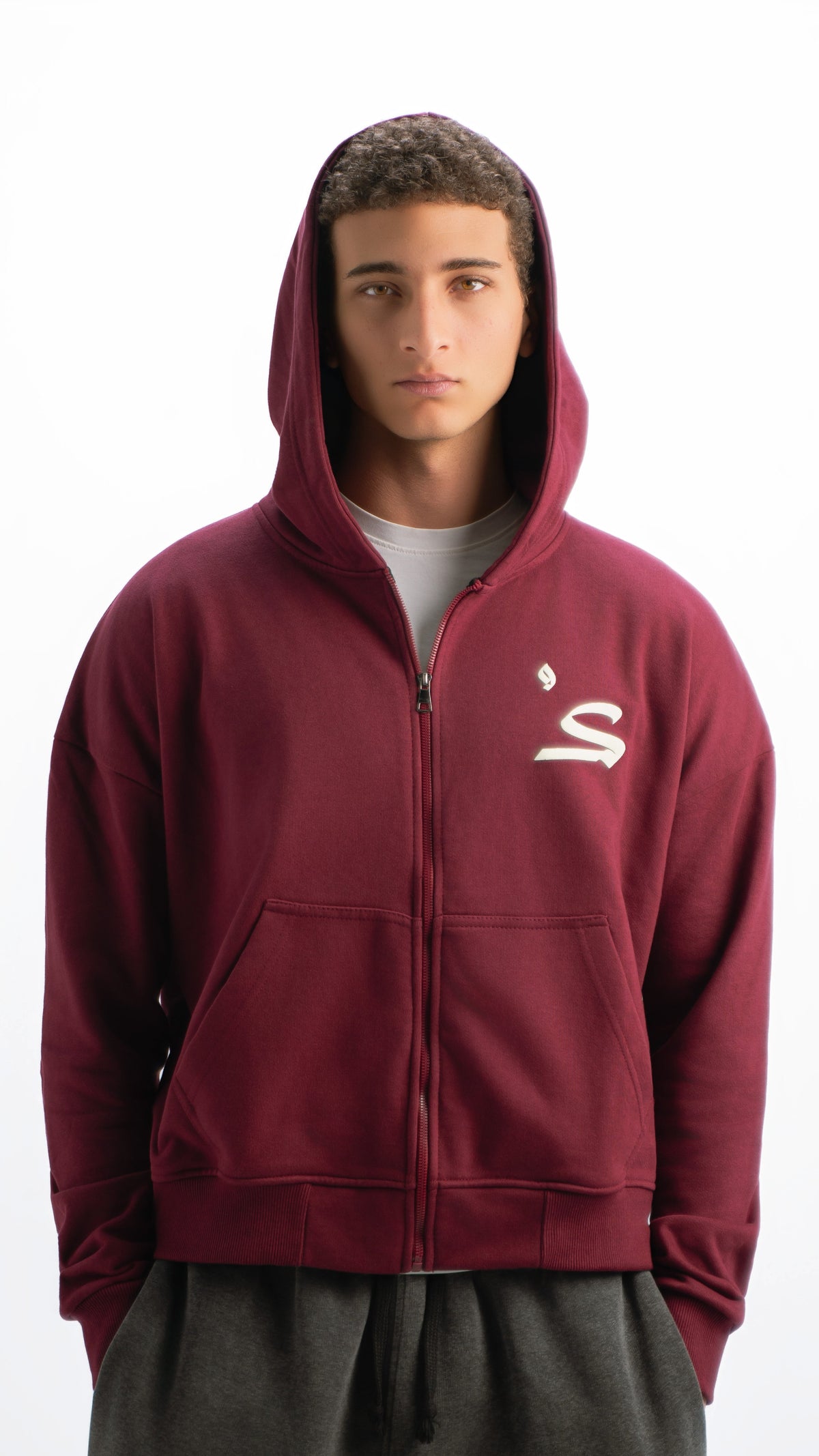 Person wearing a maroon hoodie with a logo on a white background
